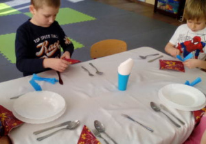 Dzieci podczas układania serwetek na stole.